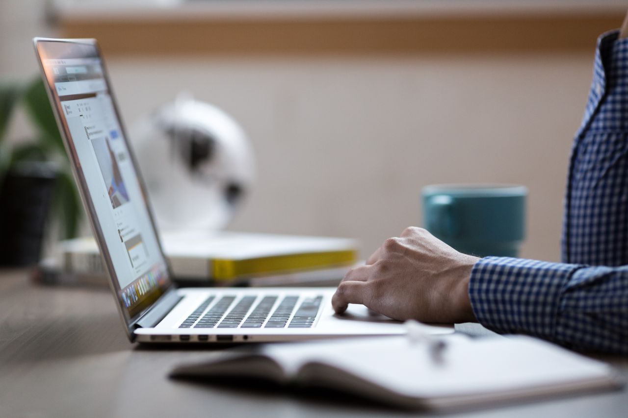 Home Business professional working on laptop at an office desk with coffee mug.