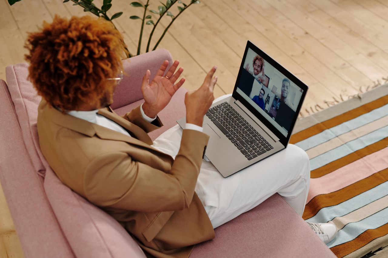 Home An adult man in a suit engages in a video call while sitting on a sofa indoors.