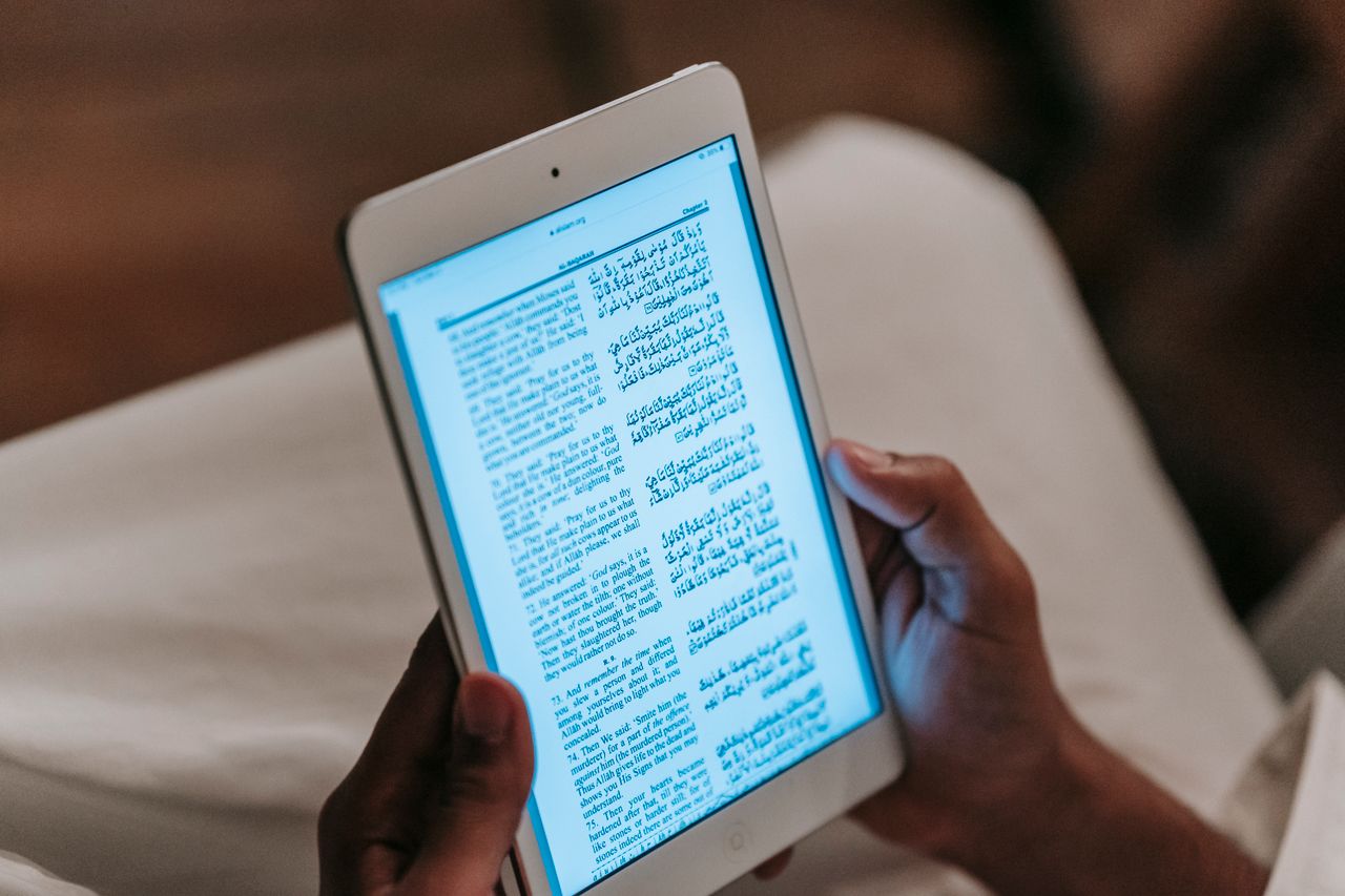 Home Crop unrecognizable person in casual clothes reading text on tablet against blurred background in room