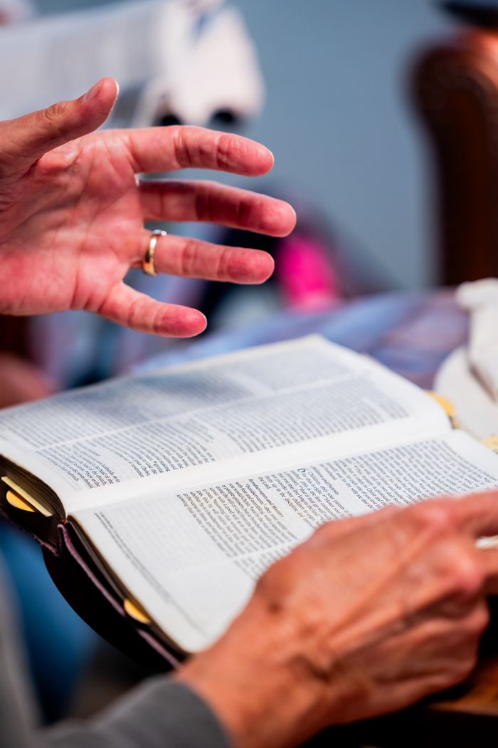 Close-up of hands engaged in Bible study at an indoor setting, promoting spiritual discussion.