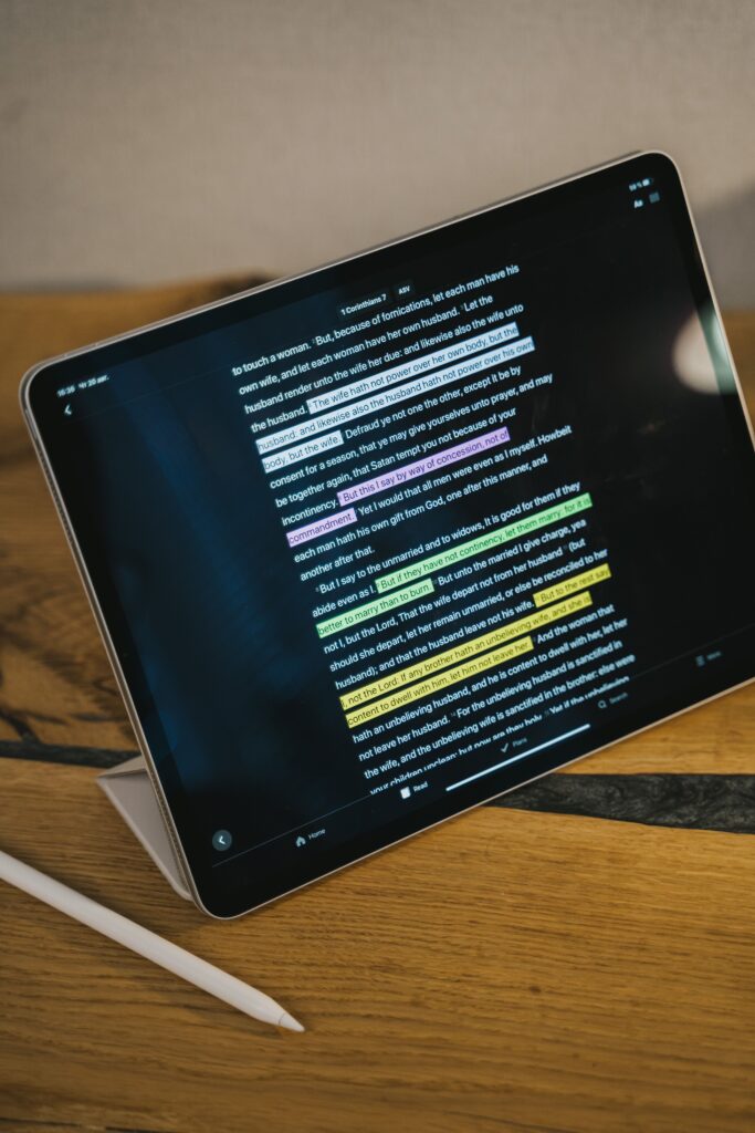 A sleek tablet with highlighted text and stylus on a wooden table, indoors.
